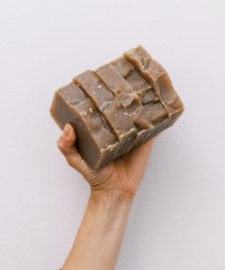 Holding five bars of handmade organic oatmeal cookie soap with exfoliating oatmeal and clove essential oil
