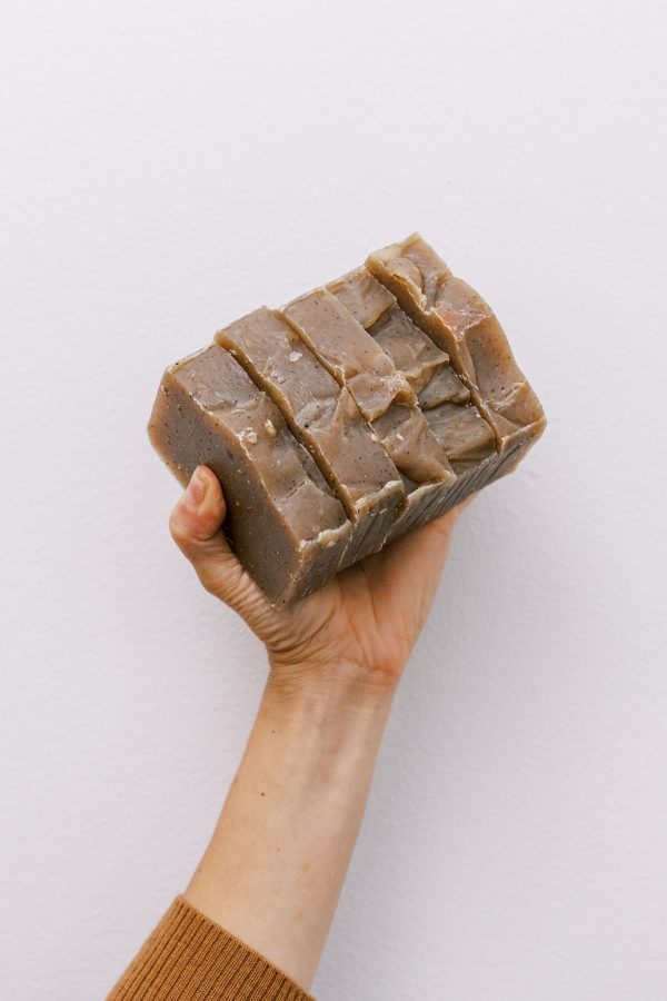 Holding five bars of handmade organic oatmeal cookie soap with exfoliating oatmeal and clove essential oil