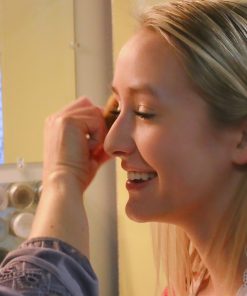 applying custom eyshadow loose mineral eyeshadow on happy girl in mirror