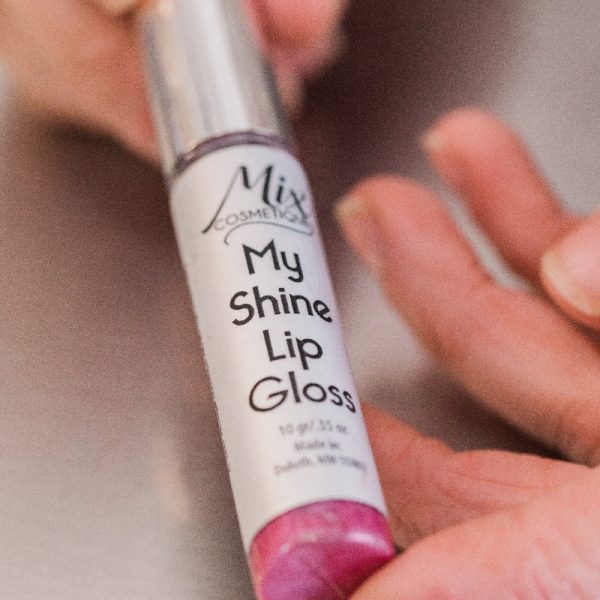 Rich results on Google's SERP when searching for "custom lip gloss" my shine custom lip gloss in tube displayed by hands in neutral pink shade good for all skin tones