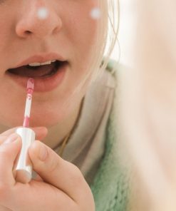 putting on custom lip gloss in the mirror after making it at the lip gloss bar