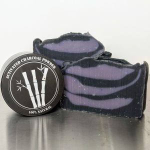 handmade, organic soap with activated charcoal powder to cleanse pores and detoxify skin, two bars of soap with container of activated charcoal, soap has purple and black swirls, scented with essential oils of lavender, bay and clove