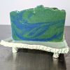 green and blue earth and water soap made with organic ingredients using an in the pot swirl method on a ceramic soap dish scented with kaffir lime and patchouli essential oils