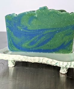 green and blue earth and water soap made with organic ingredients using an in the pot swirl method on a ceramic soap dish scented with kaffir lime and patchouli essential oils