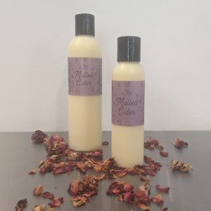two bottles of organic mulled cider lotion with rose petals and scented with essential oils