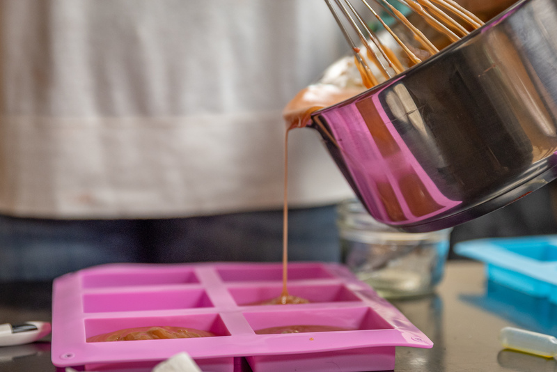 someone making Cold process soap being poured into a mold with natural colorants and essential oils at Mix Cosmetiques studio