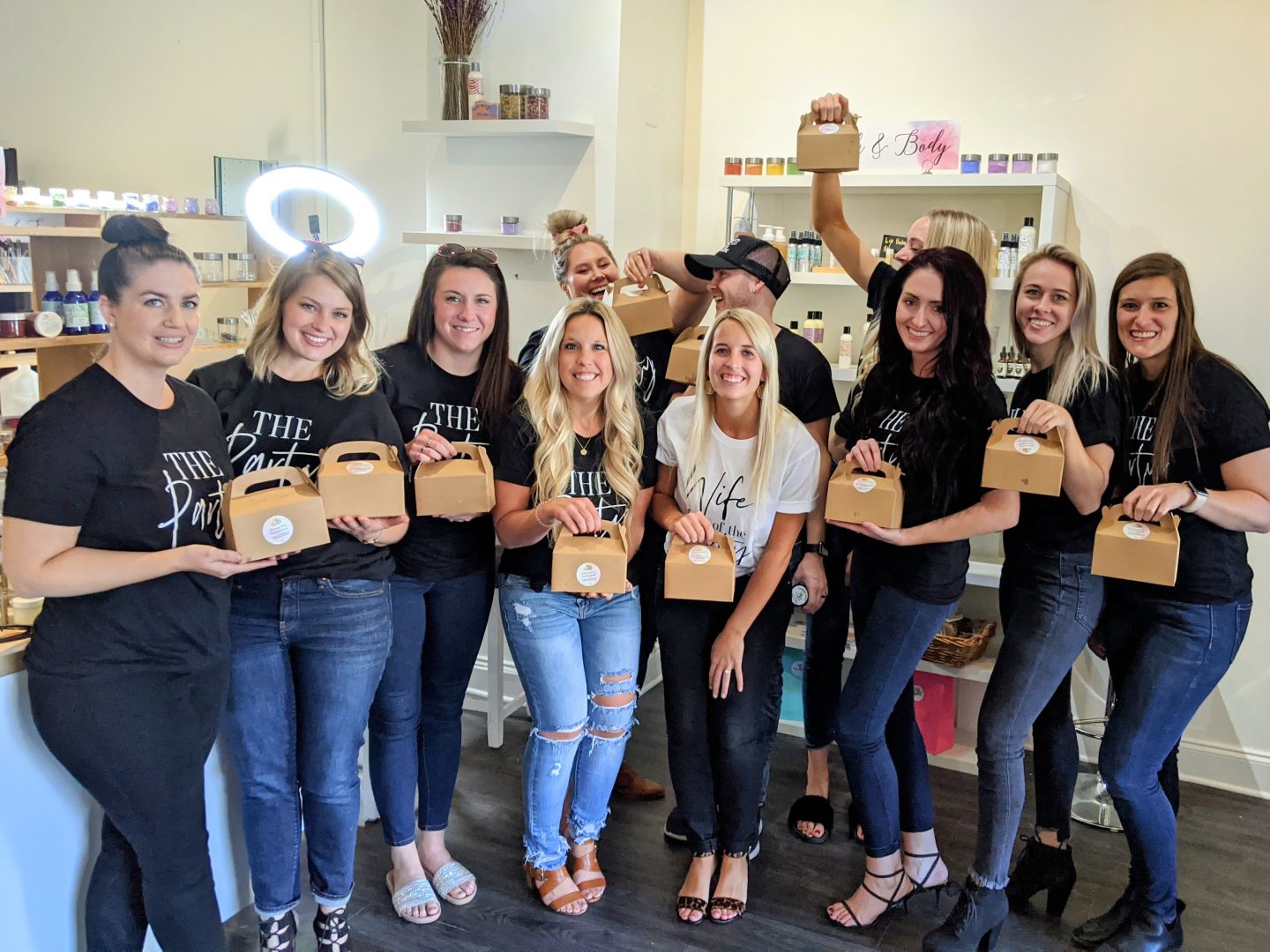 A joyful group of friends at the end of their bachelorette party at Mix Cosmetiques, proudly holding their custom-made beauty products like lip gloss, bath bombs, and bespoke perfumes. The group is smiling in a fun, relaxed atmosphere, showcasing the exclusive experience of creating plant-based, personalized cosmetics in Superior, WI. A one-of-a-kind celebration for brides-to-be and their friends!