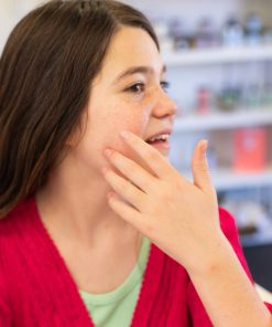 a teen girl using green apple zit zap on her skin to show it is an Invisible acne patch to avoid Acne scarring with a Natural blemish treatment and Acne-fighting botanicals