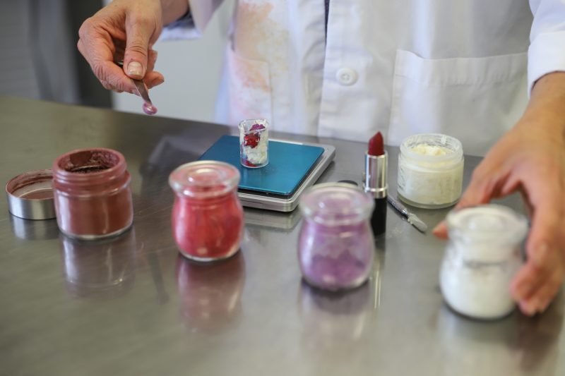 Mix Cosmetiques founder handcrafting organic custom lipstick with a customer, creating a personalized shade using natural, clean ingredients.